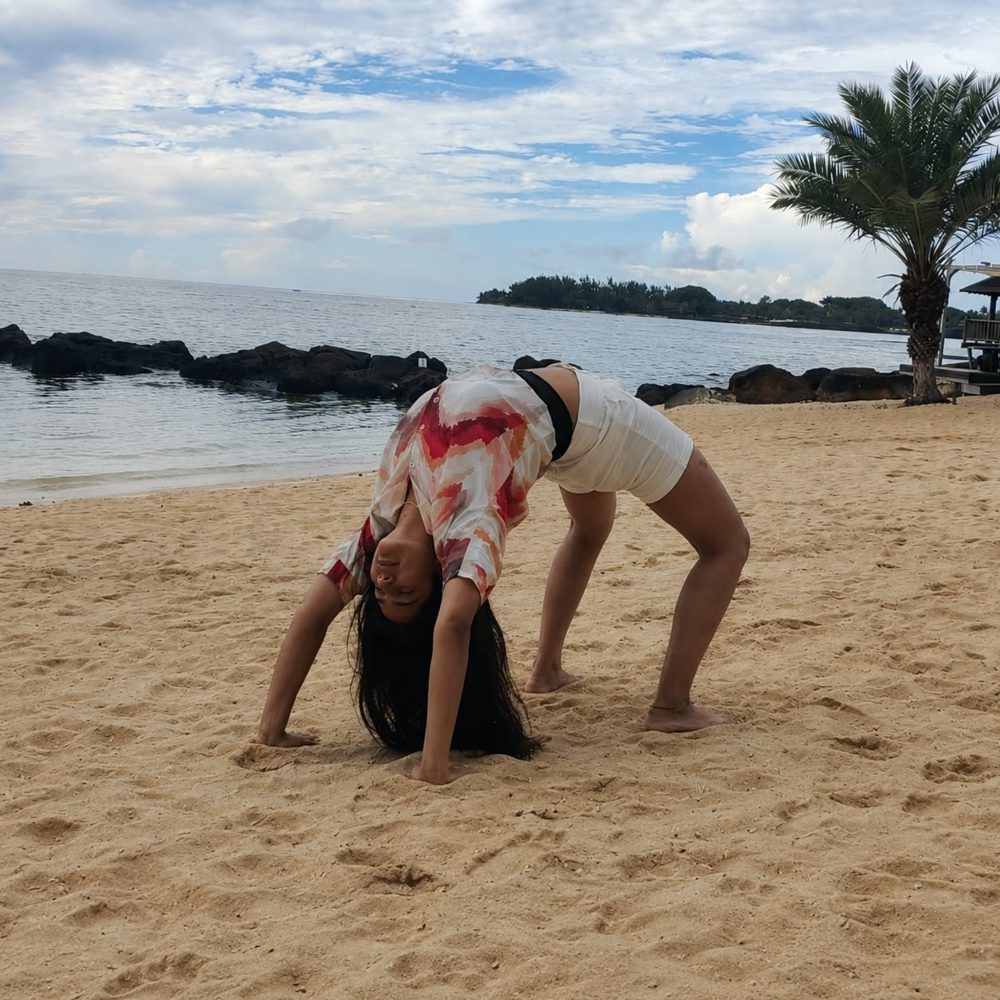 Sakshi practising Chakrasana (wheel pose) on a beach