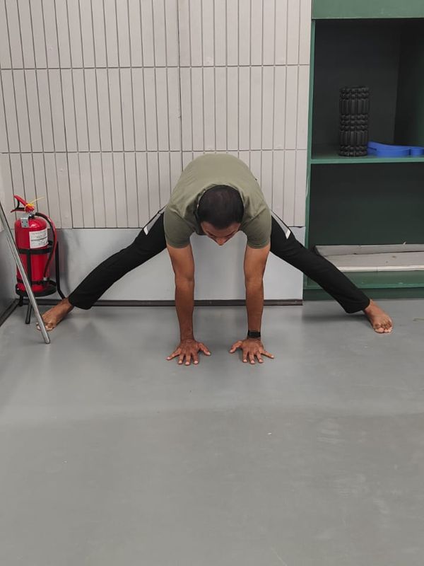 Student practising Prasarita Padottanasana (wide-leg forward fold)